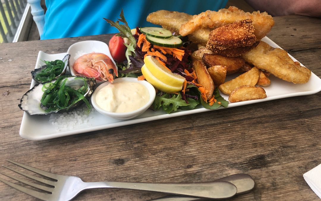 A plate of fish and chips on a wooden table, served during one of the Sunshine Coast tours.