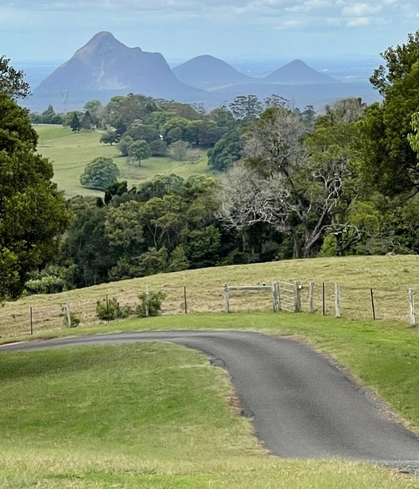 A road leading to a grassy field with mountains in the background, offering breathtaking views of the Sunshine Coast.