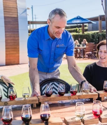 A group of people enjoying a wine tasting experience at a table in Maleny, on a Sunshine Coast tour.