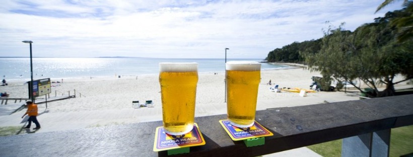 Two glasses of beer on a balcony overlooking the beach 