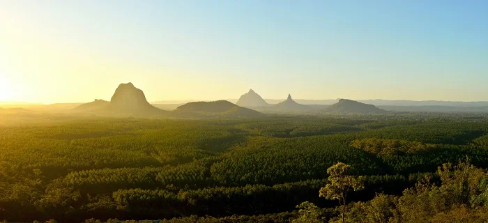 A sunrise over a mountain range with trees in the background, offering a breathtaking view for sightseers on the Sunshine Coast.